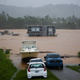 A home is submerged in murky floodwaters amid stormy weather.